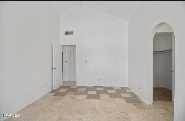 empty room featuring visible vents, beam ceiling, baseboards, high vaulted ceiling, and arched walkways