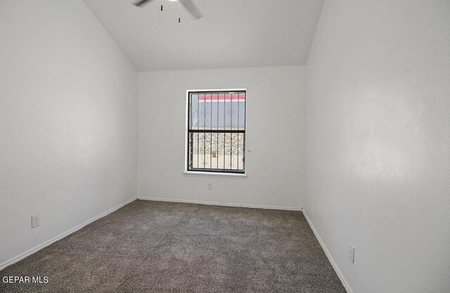 carpeted spare room with ceiling fan, vaulted ceiling, and baseboards