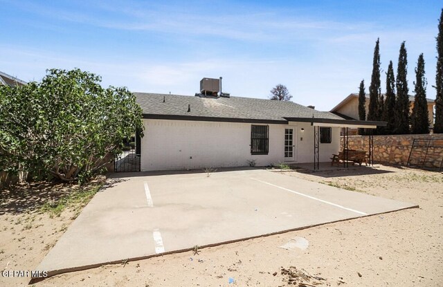 back of property with a patio, a fenced backyard, brick siding, central AC unit, and a shingled roof