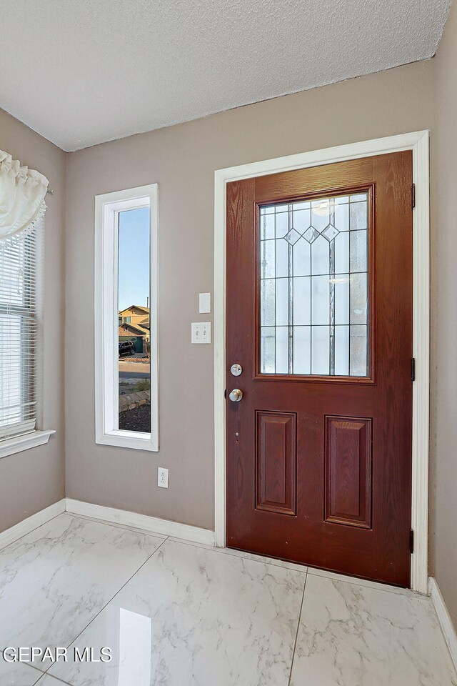 entryway with baseboards and marble finish floor
