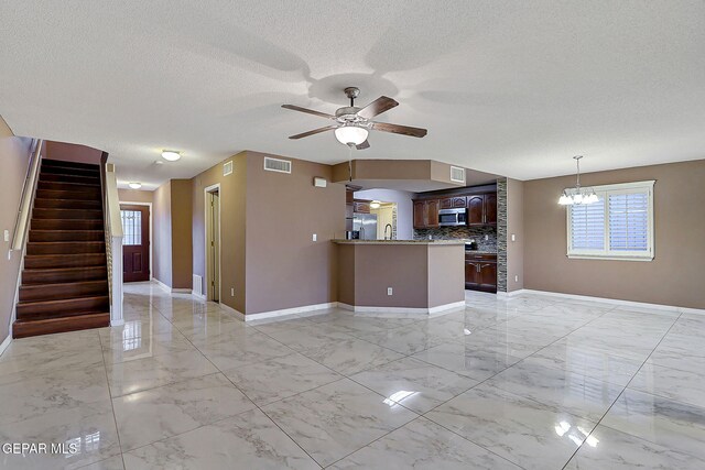 unfurnished living room with baseboards, a textured ceiling, marble finish floor, and ceiling fan with notable chandelier