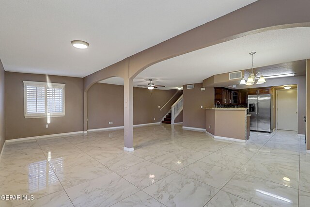 unfurnished living room featuring marble finish floor, baseboards, visible vents, and stairway