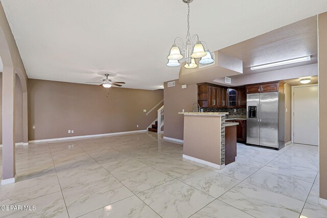 kitchen featuring marble finish floor, a peninsula, baseboards, stainless steel refrigerator with ice dispenser, and ceiling fan with notable chandelier