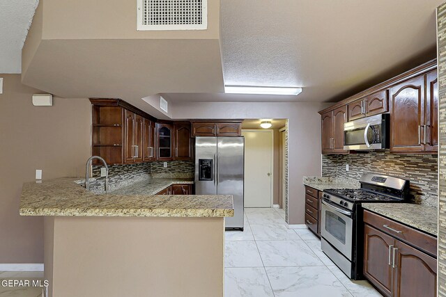 kitchen featuring decorative backsplash, visible vents, appliances with stainless steel finishes, a peninsula, and marble finish floor