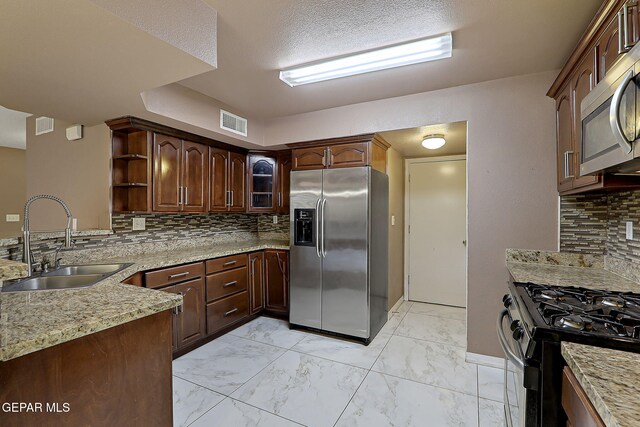 kitchen with a sink, marble finish floor, stainless steel appliances, decorative backsplash, and visible vents