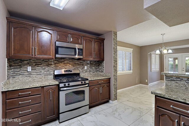 kitchen featuring marble finish floor, baseboards, backsplash, a wealth of natural light, and stainless steel appliances