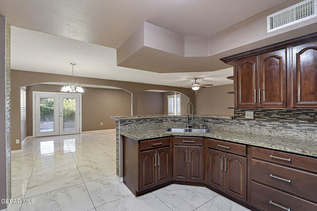 kitchen with a sink, arched walkways, marble finish floor, ceiling fan with notable chandelier, and visible vents