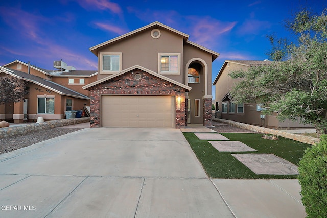 traditional-style house with concrete driveway, a garage, and stucco siding