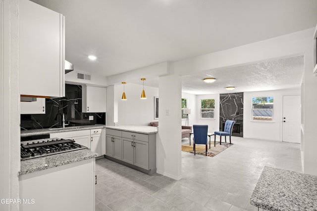 5540 Norwood Ct, El Paso, TX 79924 - kitchen featuring stainless steel gas stovetop, tasteful backsplash, light stone countertops, gray cabinetry, and pendant lighting