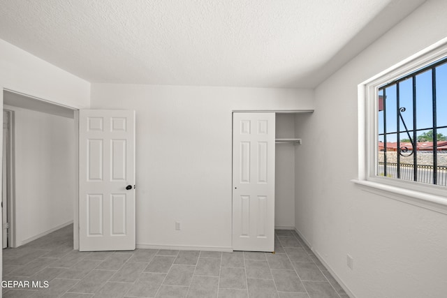 5540 Norwood Ct, El Paso, TX 79924 - unfurnished bedroom featuring a textured ceiling, a closet, light tile patterned floors, and baseboards