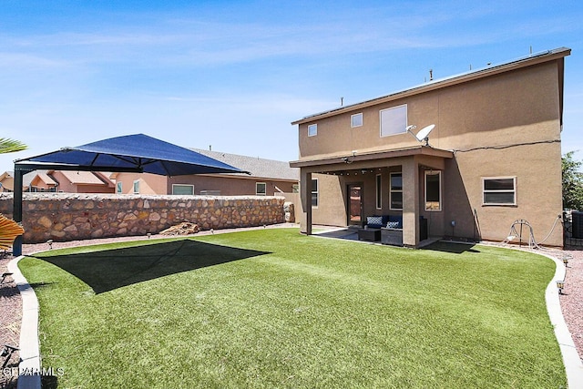 rear view of house with a patio area, a fenced backyard, outdoor lounge area, and stucco siding