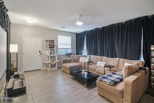 living area featuring ceiling fan, visible vents, and baseboards