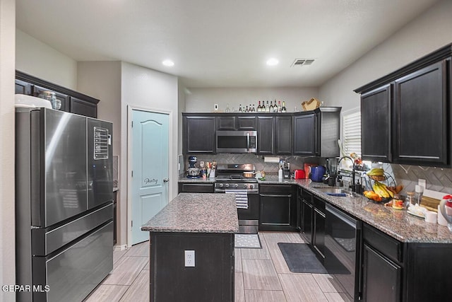 kitchen with appliances with stainless steel finishes, decorative backsplash, a sink, and visible vents