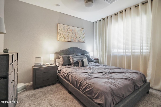 bedroom featuring a ceiling fan, visible vents, carpet floors, baseboards, and a textured wall