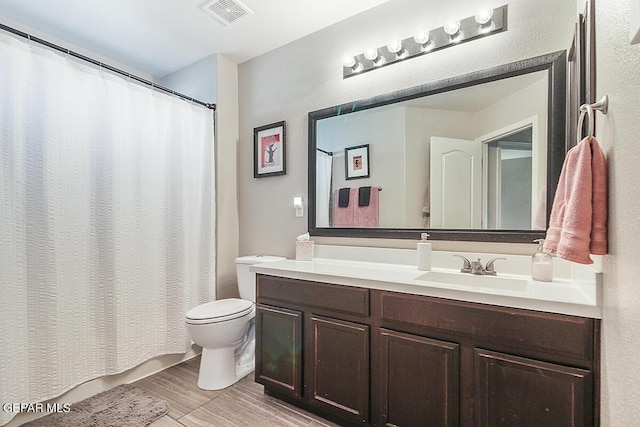 bathroom with a shower with curtain, visible vents, wood finished floors, vanity, and toilet