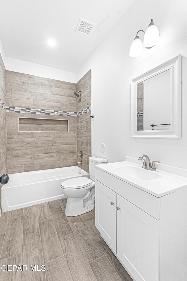 bathroom with vanity, shower / bathtub combination, toilet, wood finished floors, and visible vents