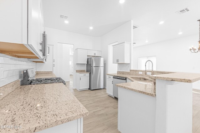 kitchen featuring visible vents, a peninsula, a sink, appliances with stainless steel finishes, and backsplash