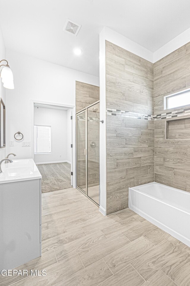 bathroom with visible vents, vanity, a washtub, wood tiled floor, and a tile shower