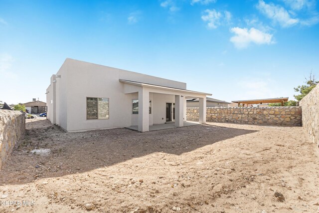 rear view of property with a fenced backyard, stucco siding, and a patio area