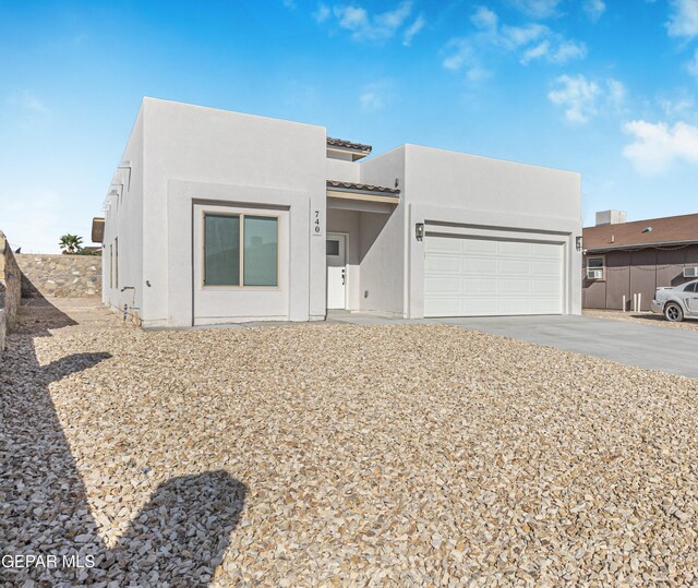 view of front of house with concrete driveway, a tiled roof, an attached garage, and stucco siding