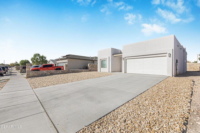 view of front facade with an attached garage, driveway, and stucco siding