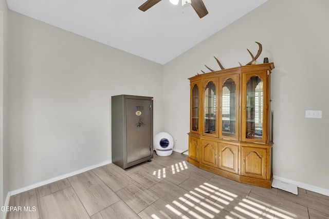 spare room featuring baseboards, a ceiling fan, light wood-type flooring, and lofted ceiling