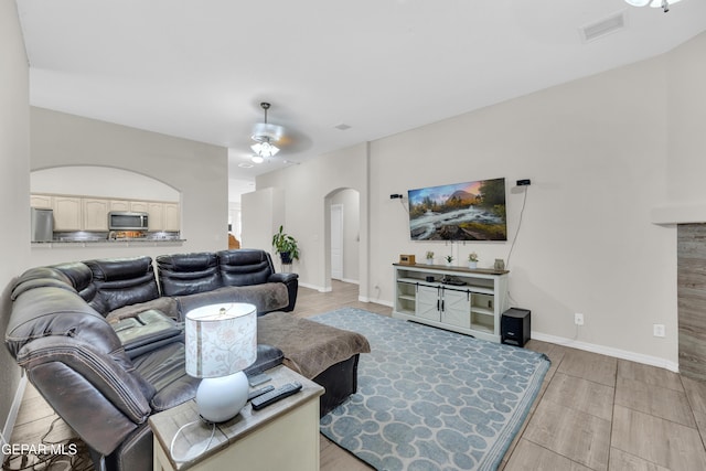 living room featuring visible vents, baseboards, ceiling fan, wood finish floors, and arched walkways