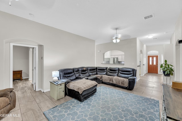 living area with arched walkways, baseboards, wood finish floors, and visible vents