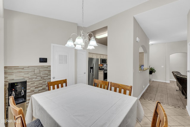 dining space featuring arched walkways, light tile patterned floors, and a notable chandelier