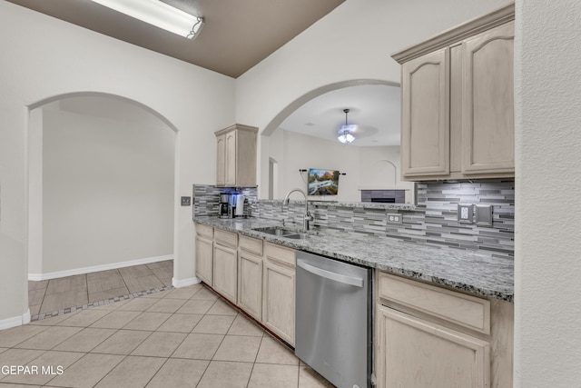 kitchen with a sink, light brown cabinets, dishwasher, arched walkways, and decorative backsplash
