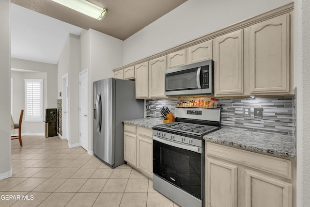 kitchen with appliances with stainless steel finishes, backsplash, light tile patterned flooring, and light brown cabinetry