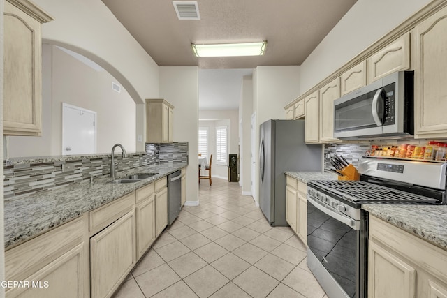 kitchen featuring decorative backsplash, visible vents, a sink, light tile patterned floors, and stainless steel appliances