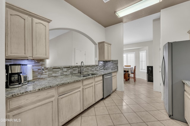 kitchen with light brown cabinets, light tile patterned floors, a sink, appliances with stainless steel finishes, and backsplash
