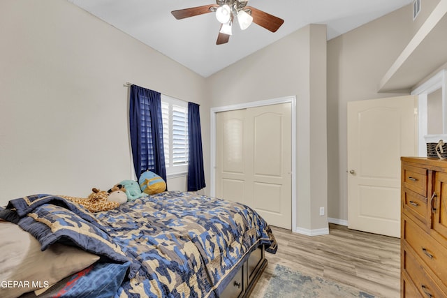 bedroom with light wood finished floors, visible vents, baseboards, vaulted ceiling, and a closet