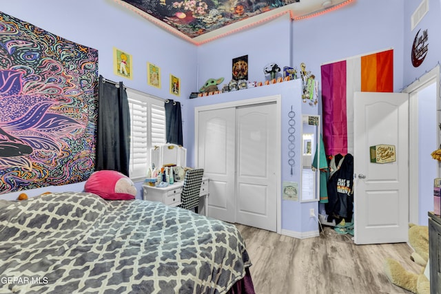 bedroom with visible vents, wood finished floors, and a closet