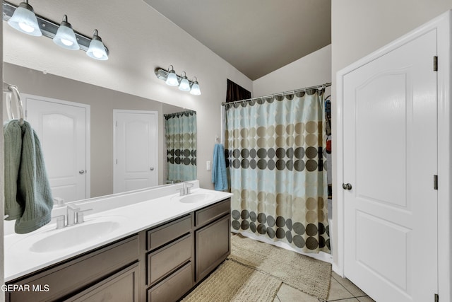 bathroom featuring a sink, tile patterned floors, double vanity, and lofted ceiling