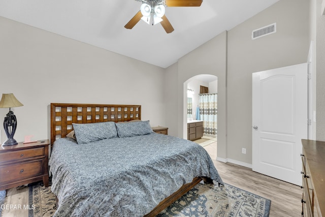 bedroom with visible vents, high vaulted ceiling, connected bathroom, arched walkways, and light wood-style flooring