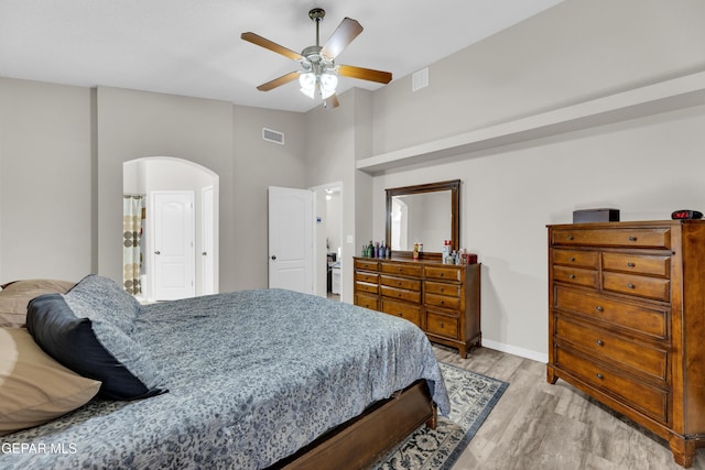 bedroom with visible vents, arched walkways, light wood finished floors, and baseboards