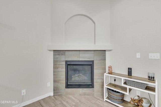 interior details featuring a tiled fireplace and baseboards