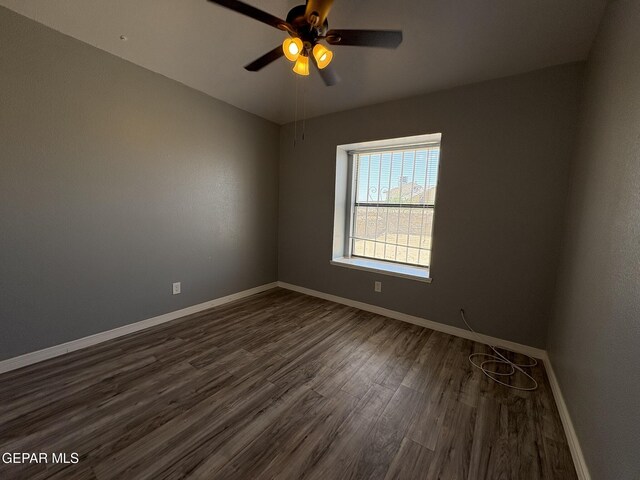 unfurnished room featuring baseboards, a ceiling fan, and dark wood-style flooring