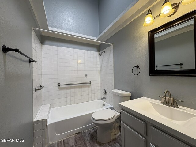 bathroom with vanity, a textured wall, shower / bathtub combination, wood finished floors, and toilet