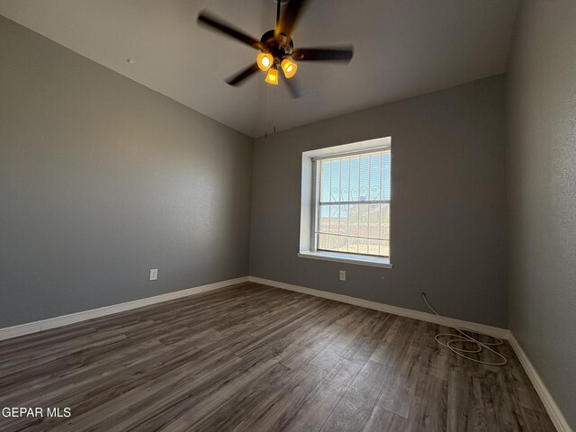 spare room with baseboards, a ceiling fan, and dark wood-type flooring