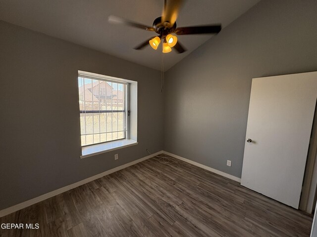 spare room featuring dark wood-type flooring, a ceiling fan, baseboards, and lofted ceiling