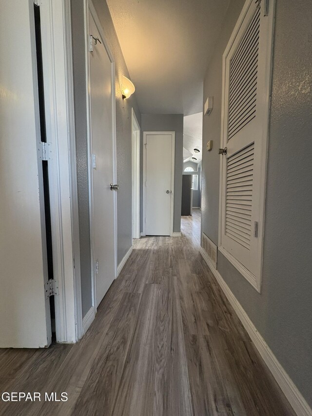 corridor featuring baseboards, wood finished floors, and visible vents