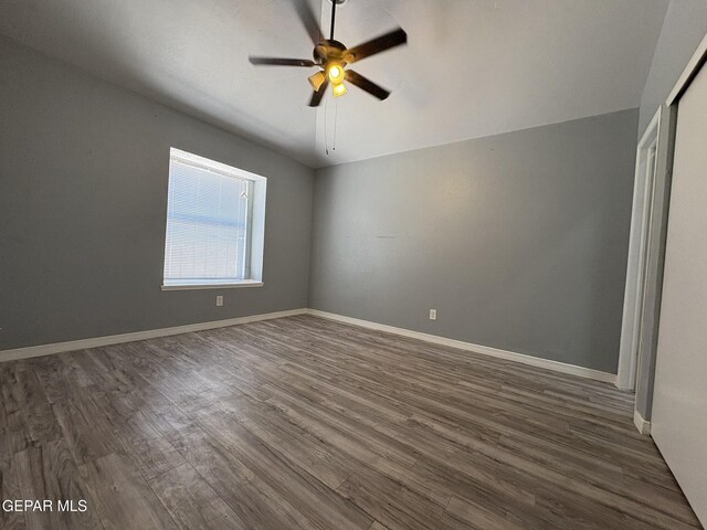 unfurnished bedroom with baseboards, a ceiling fan, dark wood finished floors, and a closet