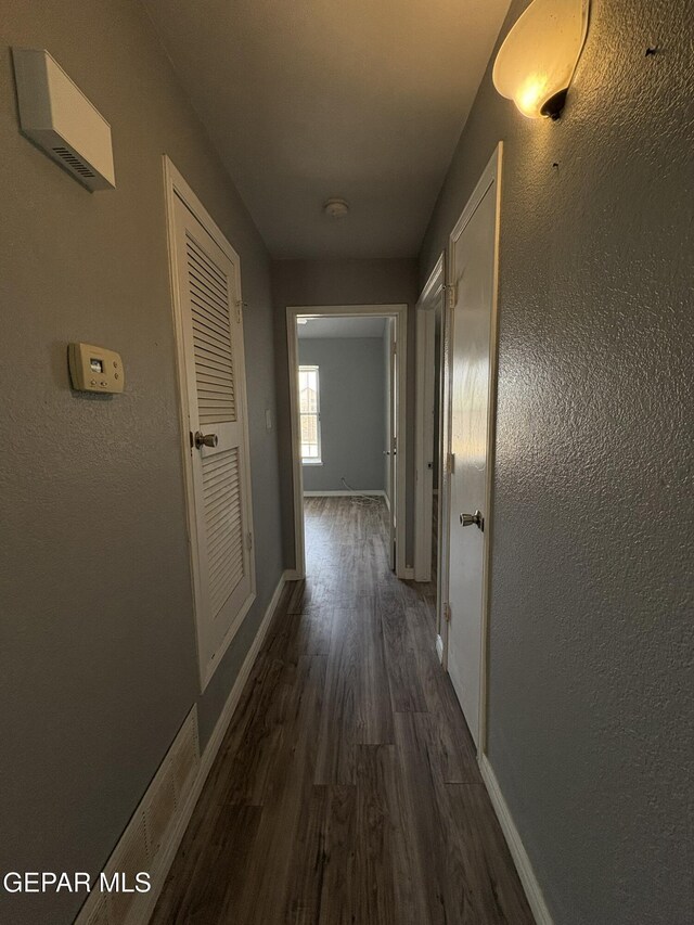 hallway featuring baseboards and wood finished floors