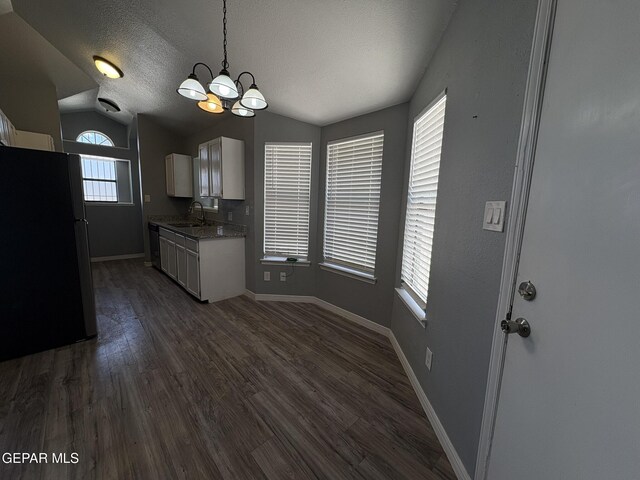 kitchen featuring freestanding refrigerator, baseboards, a chandelier, dishwasher, and vaulted ceiling