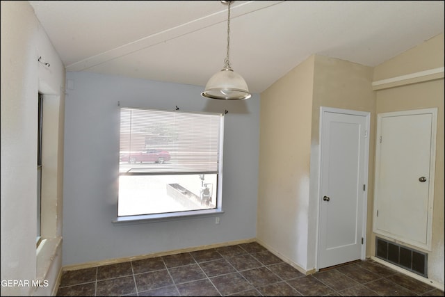 unfurnished dining area featuring dark tile patterned floors, baseboards, and visible vents