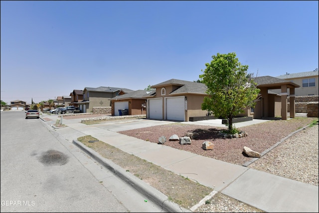 view of front of house featuring an attached garage, driveway, a residential view, and stucco siding