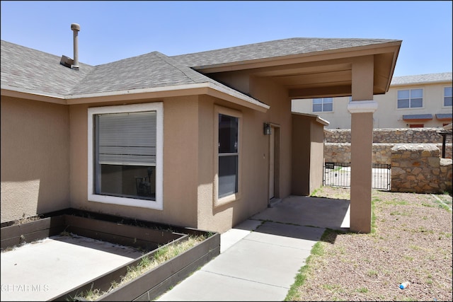 view of side of property featuring fence, roof with shingles, and stucco siding